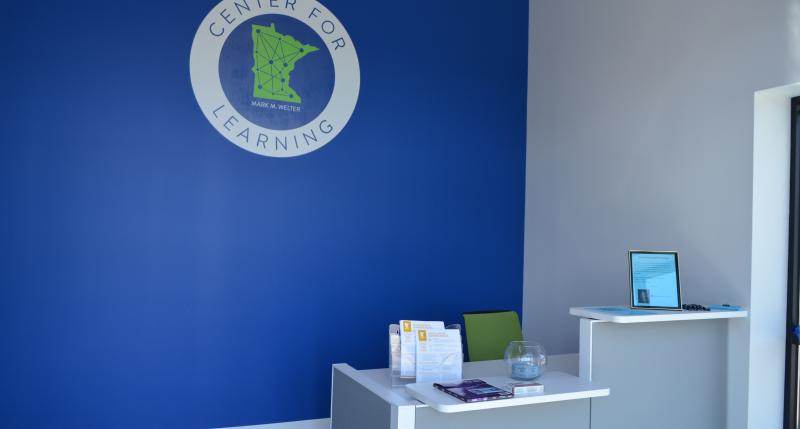 Front desk against blue wall with Center logo featured on the wall
